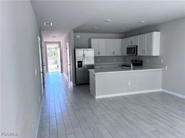 a kitchen with wooden floors and white stainless steel appliances
