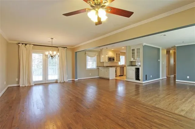 a view of an empty room with window and wooden floor
