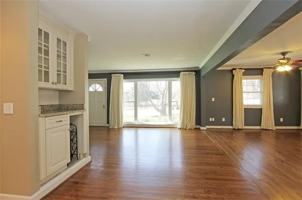 a view of an empty room with window and wooden floor