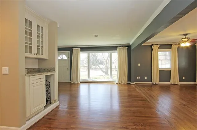 a view of an empty room with window and wooden floor