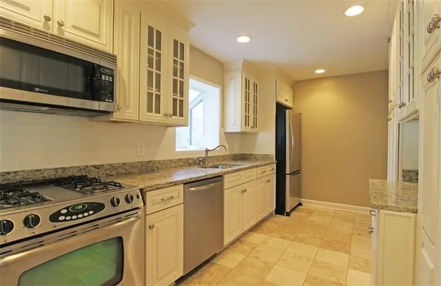 a kitchen with stainless steel appliances granite countertop a stove a sink and a refrigerator