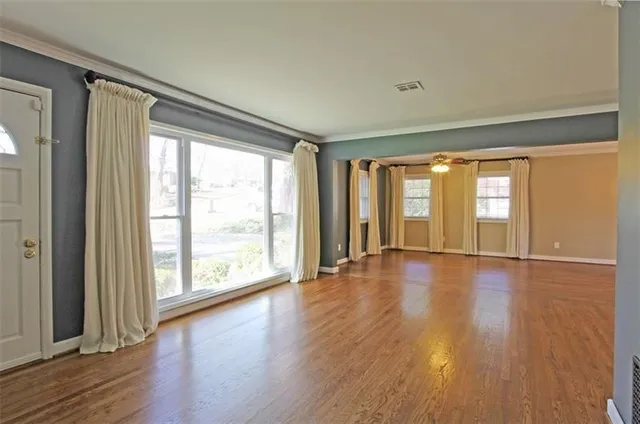 a view of an empty room with wooden floor and a window
