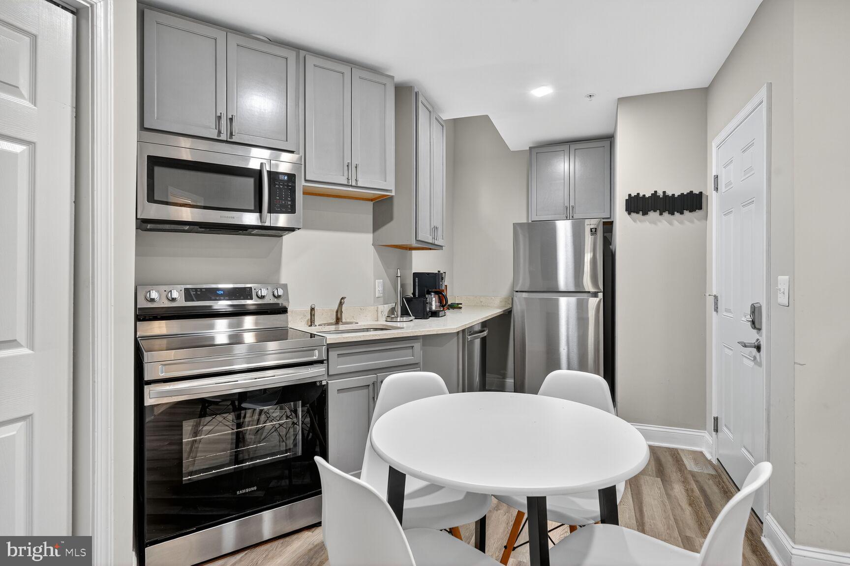133 7th Street Southeast, Unit 3 Washington, DC 20003 - Photo 5 of 19 a kitchen with stainless steel appliances granite countertop a refrigerator a stove a sink dishwasher and white cabinets with wooden floors