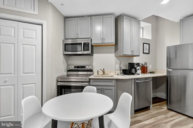 a kitchen with stainless steel appliances a dining table chairs refrigerator and cabinets