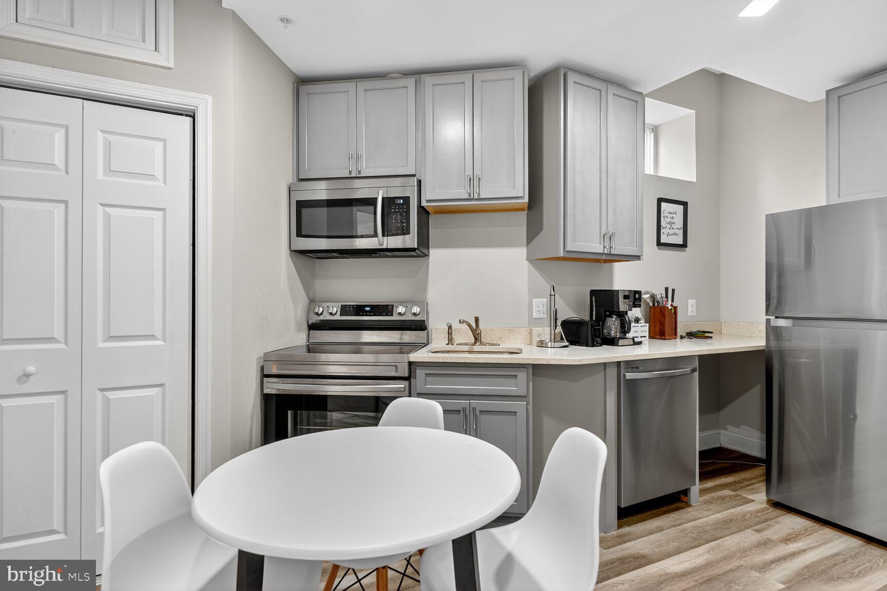 133 7th Street Southeast, Unit 3 Washington, DC 20003 - Photo 6 of 19 a kitchen with stainless steel appliances a dining table chairs refrigerator and cabinets