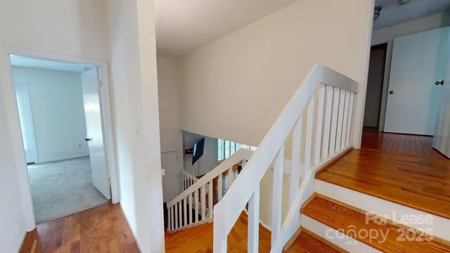 a view of a hallway with wooden floor and stairs