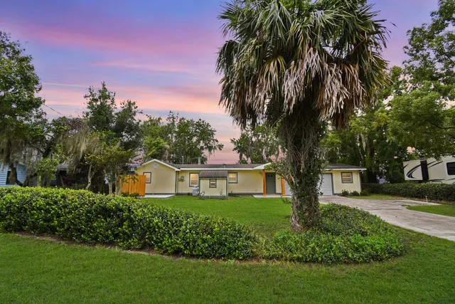 a front view of a house with a garden and trees