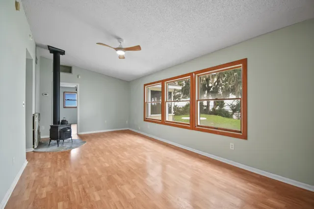 a view of an empty room with a window and wooden floor