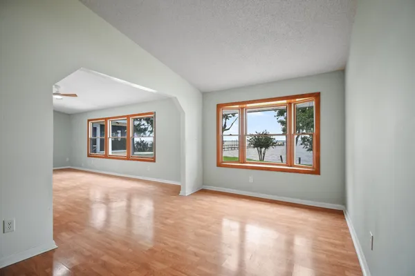 a view of an empty room with a window and wooden floor