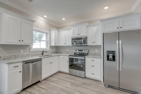 a kitchen with white cabinets stainless steel appliances and a sink