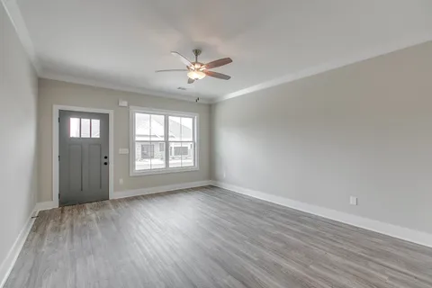a view of an empty room with a window and wooden floor
