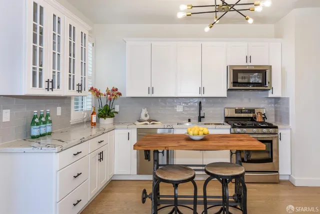 a kitchen with stainless steel appliances a stove a sink and white cabinets