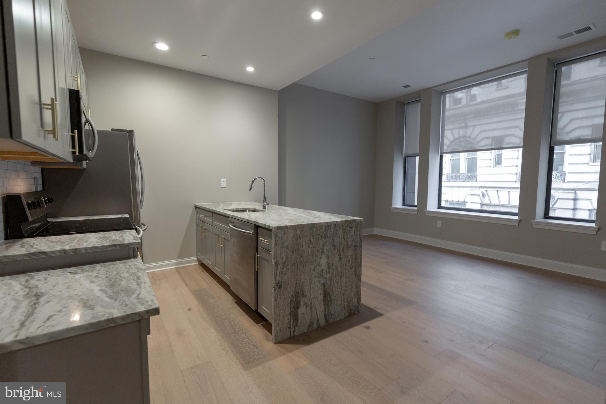 1411-1 Walnut Street, Unit 201 Philadelphia, PA 19102 - Photo 6 of 27 a kitchen with kitchen island sink stainless steel appliances and window