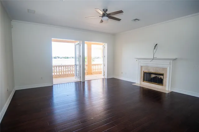 a view of an empty room with wooden floor fireplace and a window