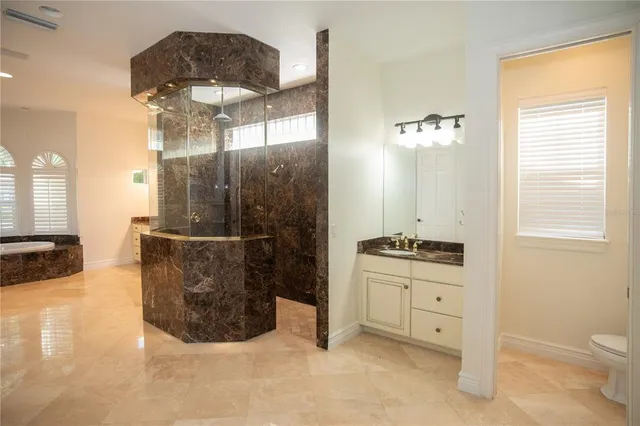 a spacious bathroom with a granite countertop sink a toilet a mirror and shower