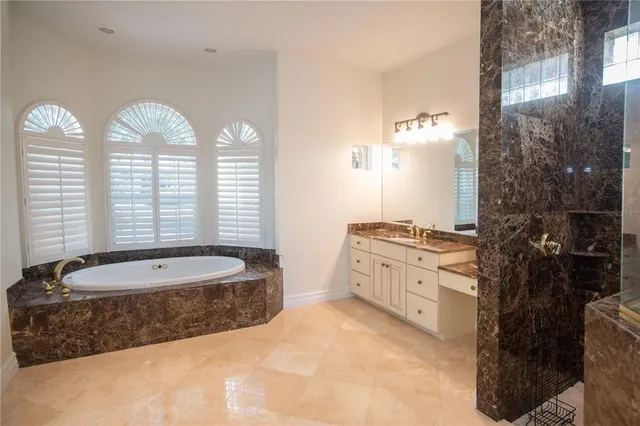 a spacious bathroom with a granite countertop tub a double vanity sink a mirror and a shower