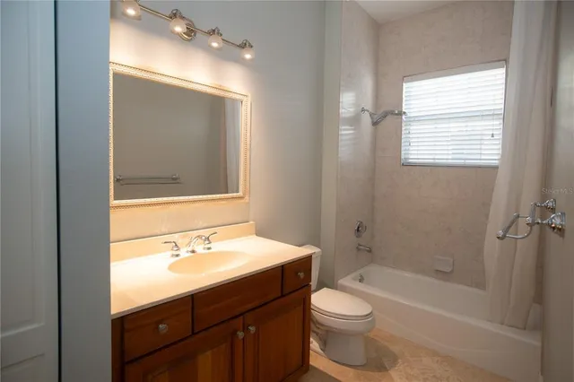 a bathroom with a bathtub shower sink vanity mirror and toilet