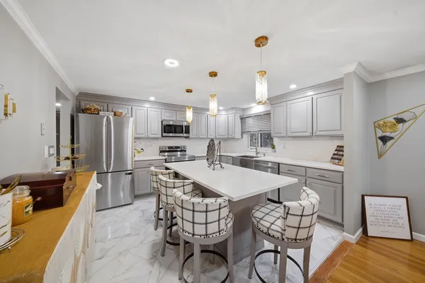 a kitchen with stainless steel appliances a sink a stove a refrigerator cabinets and dining table