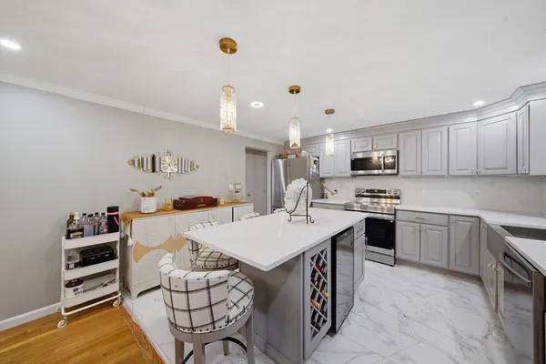a large kitchen with kitchen island white cabinets and stainless steel appliances
