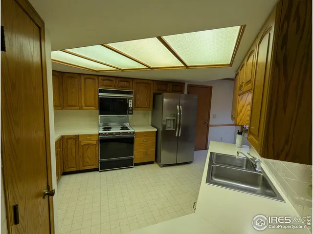 a kitchen with stainless steel appliances granite countertop a refrigerator a sink and white cabinets
