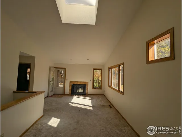 an empty room with windows and fireplace