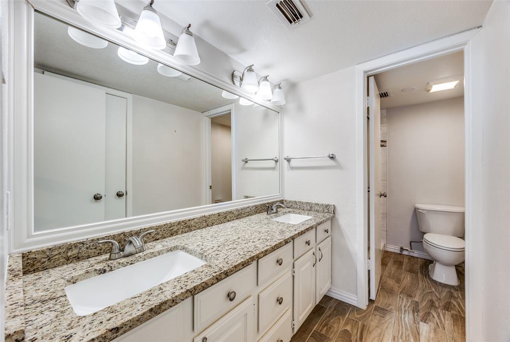 13220 Woodbend Lane Dallas, TX 75243 - Photo 17 of 26 a spacious bathroom with a granite countertop sink a toilet a mirror and shower