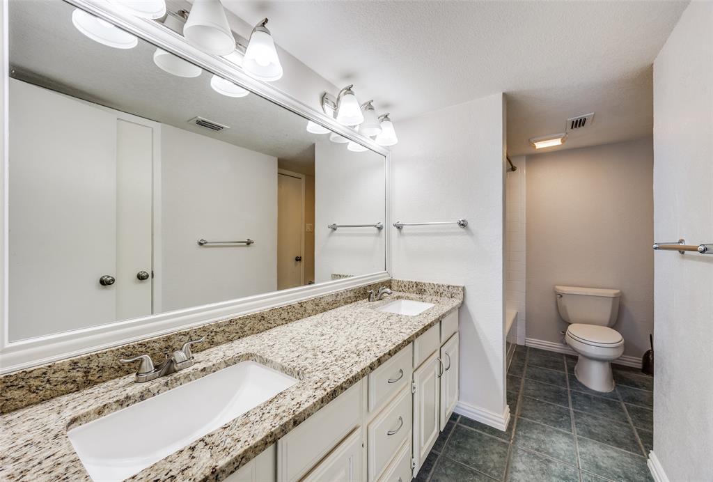 13220 Woodbend Lane Dallas, TX 75243 - Photo 20 of 26 a bathroom with a granite countertop sink a toilet and a shower