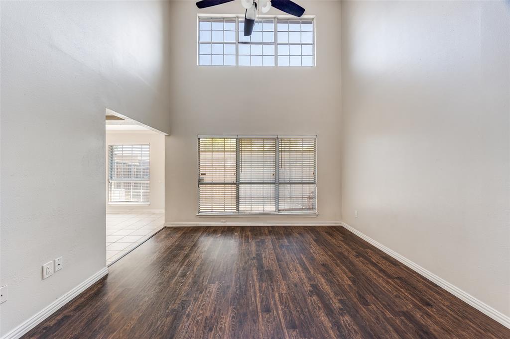 13220 Woodbend Lane Dallas, TX 75243 - Photo 6 of 26 an empty room with wooden floor chandelier and windows