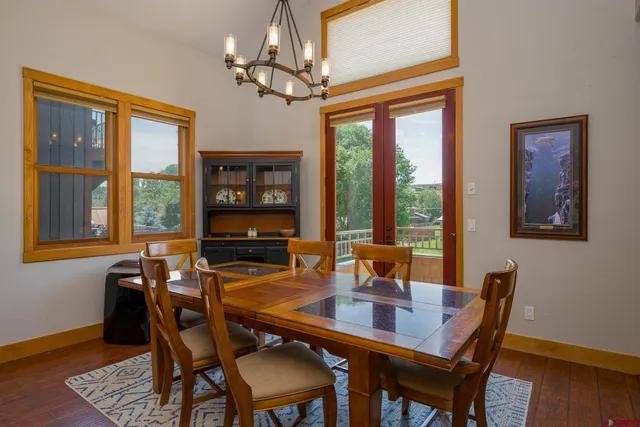 a dining room with wooden floor a chandelier a wooden table and chairs