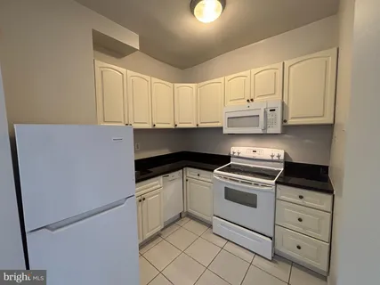 a kitchen with granite countertop white cabinets and white appliances