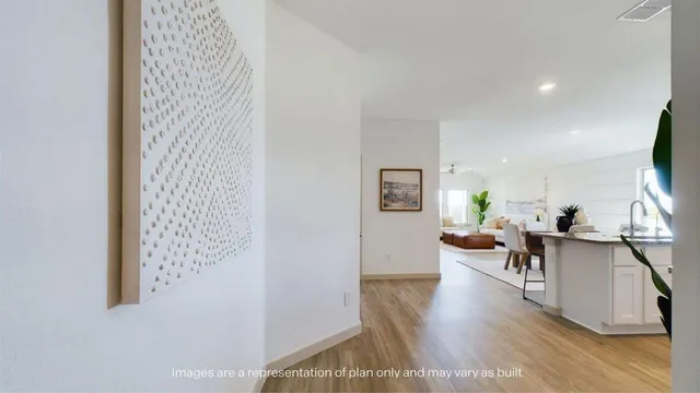an empty room with an entryway and kitchen view