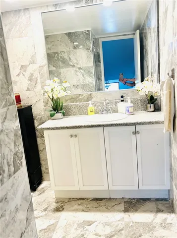 a room with granite countertop a sink and a mirror