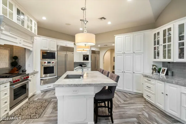a kitchen with stainless steel appliances a stove a sink a oven a dining table and chairs
