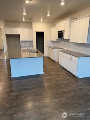 a large kitchen with stainless steel appliances a sink a stove top oven a counter space and cabinets