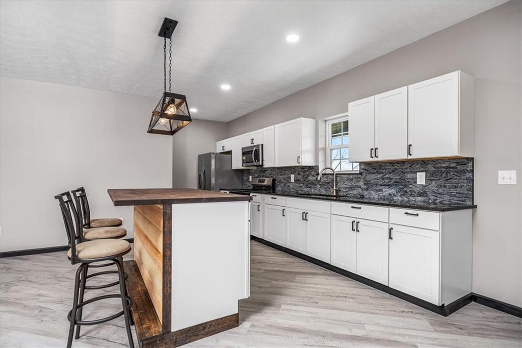 300 3rd Street Langeloth, PA 15054 - Photo 11 of 38 a kitchen with stainless steel appliances granite countertop a stove a sink dishwasher a refrigerator and white cabinets with wooden floor