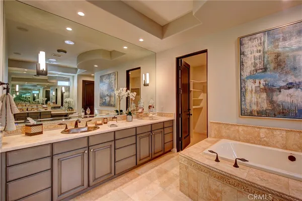a bathroom with a tub a double vanity sink and mirror