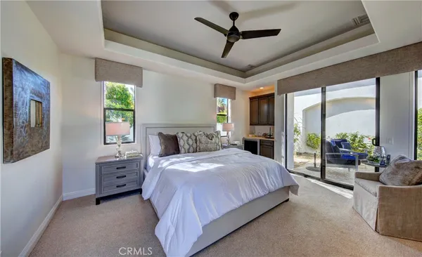 a bedroom with a large bed a flat screen tv and a chandelier