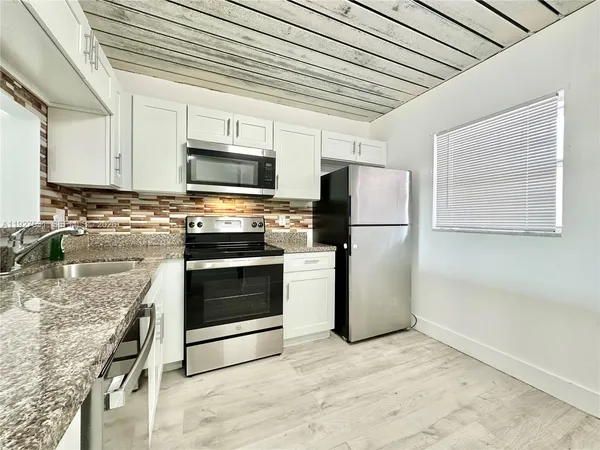 a kitchen with granite countertop white cabinets and white appliances