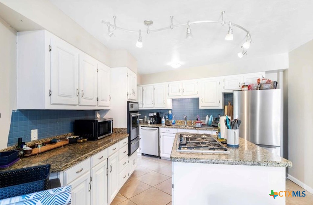 503 Rabbit Run Road Victoria, TX 77905 - Photo 8 of 20 a large kitchen with stainless steel appliances granite countertop a stove a sink a refrigerator and white cabinets