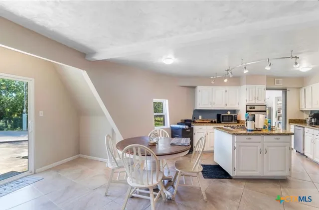 a kitchen with a dining table chairs and white cabinets