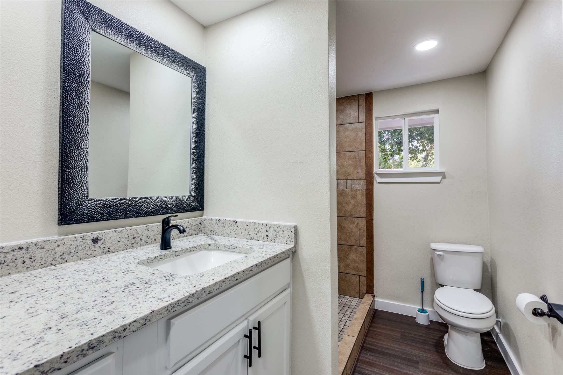 1118 Spur Street Austin, TX 78721 - Photo 11 of 21 A well-lit bathroom with granite counters, a spacious vanity, and a shower with tiled walls.