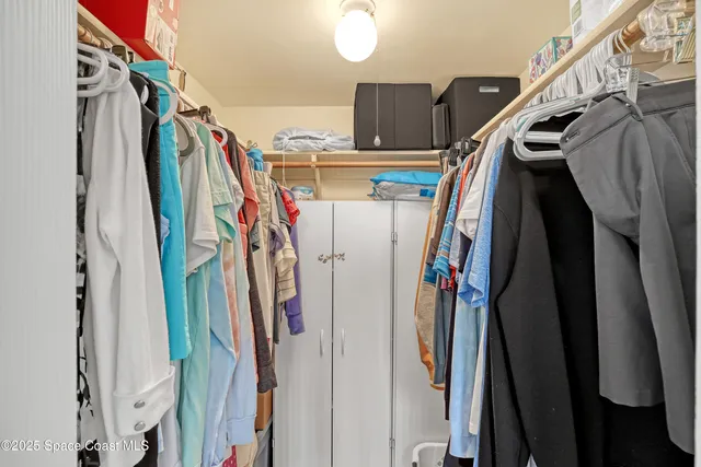a view of walk in closet with clothes and shoes