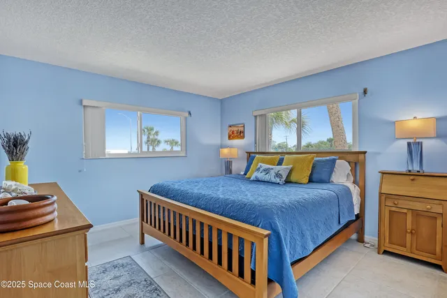 a bedroom with a bed a dresser and painting on the wall