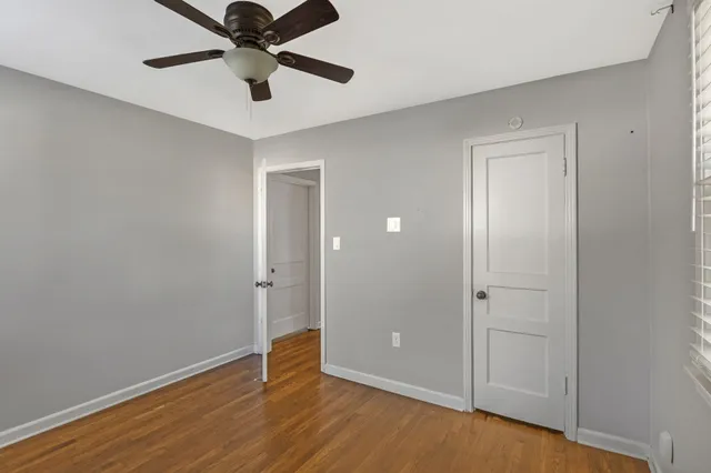 an empty room with wooden floor closet and ceiling fan