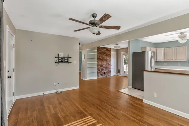 a view of empty room with wooden floor and fan