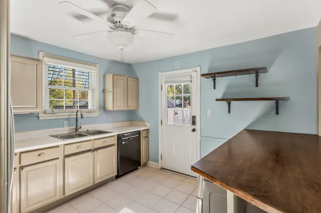 a kitchen with a sink dishwasher a stove and white cabinets with wooden floor