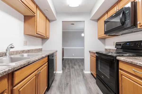 a kitchen with stainless steel appliances granite countertop a sink dishwasher stove and microwave with wooden cabinets