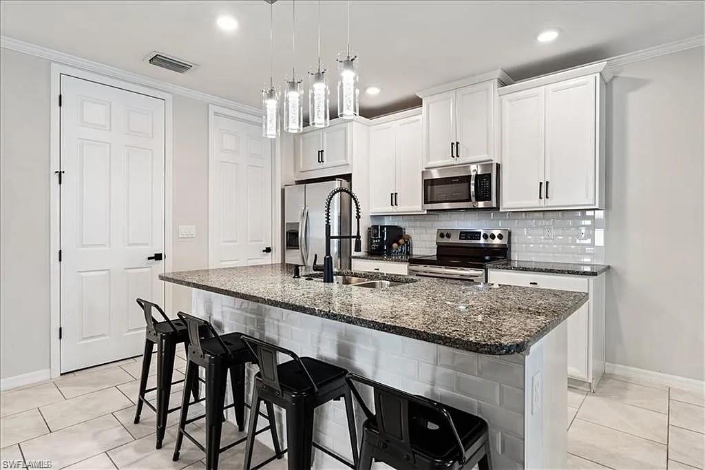 14672 Edgewater Circle Naples, FL 34114 - Photo 6 of 41 a kitchen with stainless steel appliances granite countertop a stove a sink and a microwave