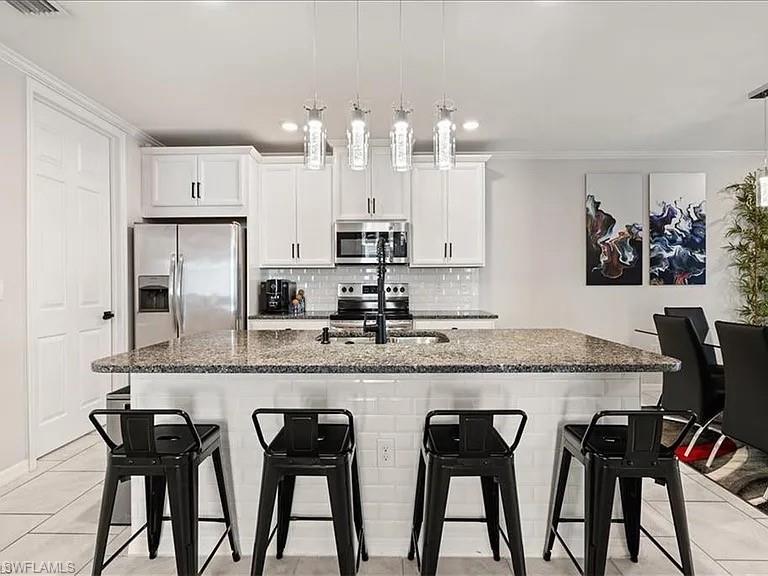 14672 Edgewater Circle Naples, FL 34114 - Photo 7 of 41 a kitchen with stainless steel appliances granite countertop a table chairs stove and white cabinets