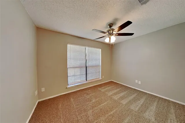 an empty room with windows and ceiling fan
